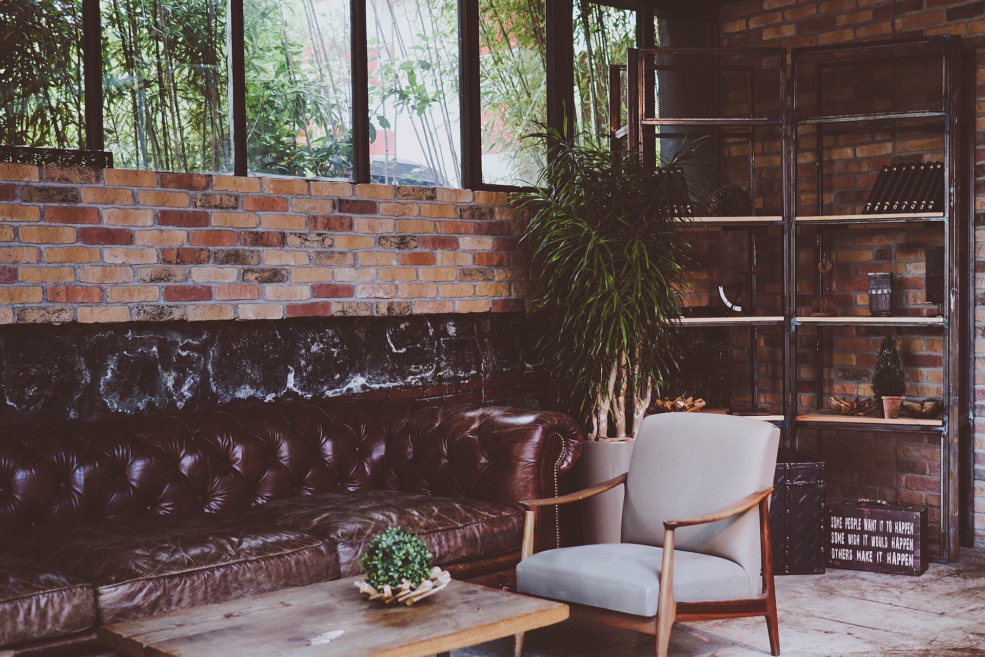 Sala de estar com sofá, poltronas e uma planta junto à janela